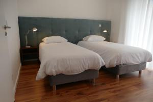 莱里亚Guest House Eça - Centro Histórico Leiria的卧室内的两张床,配有白色床单和枕头