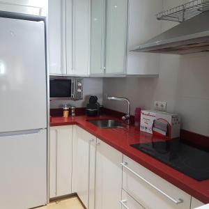 贝尼多姆Las Damas Piso18的厨房配有白色橱柜和红色台面