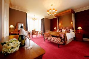 因弗内斯力推尼斯湖乡村宅邸酒店的大型酒店客房设有一张床铺和一张桌子。