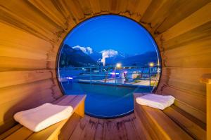 萨莱切Ibis Styles Sallanches Pays du Mont-Blanc的木制桑拿房的圆形窗户,设有游泳池