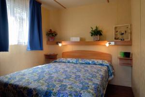 卡瓦利诺卡伯顿村酒店的一间卧室配有一张带蓝色棉被的床