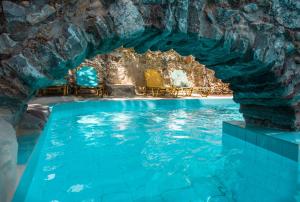 MaláxaMalaxiana Houses的水中带蓝色椅子的洞穴游泳池