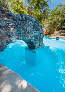 MaláxaMalaxiana Houses的一座拥有石墙和蓝色海水的游泳池