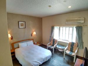 Liugui芳晨温泉渡假村 的一间卧室配有一张床、两把椅子和一个窗户