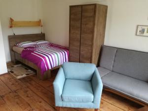 洛克特乌布特瓦尼帕德杰柘木公寓的一间卧室配有一张床、一把椅子和一张沙发