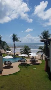 伊塔齐米林Bali Bahia Itacimirim的海滩旁带桌子和遮阳伞的游泳池