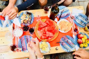 第比利斯Bude Hostel的一群人坐在桌子旁,一边吃着食物和葡萄酒