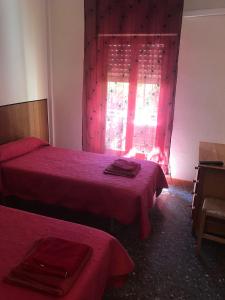 奥罗佩萨德尔马乐斯科拉塔旅舍的一间卧室设有两张床,窗户配有红色床单。