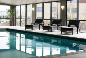 奥克兰苏迪马酒店的一座带桌椅的游泳池位于大楼旁