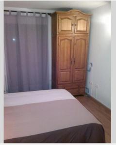 布罗托Completo Broto的一间卧室配有一张床和一个木制橱柜