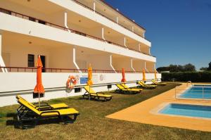 奎特里拉索尔加维公寓式酒店的游泳池旁的酒店拥有椅子和遮阳伞