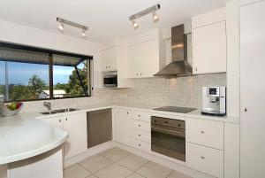 努萨角准将公寓的厨房配有白色橱柜、水槽和窗户。
