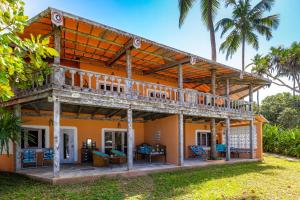 迪亚尼海滩Nomad Beach Resort的一座橙色的房子,设有阳台,并种植了棕榈树