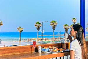 特拉维夫普里曼特拉维夫酒店的坐在桌子旁喝一杯,坐在沙滩上的女人