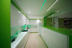 乌雷基Green House的白色的大厨房,设有绿色的墙壁和白色的橱柜