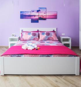 拉古萨Casa Rossini的卧室配有白色床和粉红色床罩