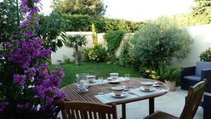 阿维尼翁L'Hibiscus Chambre d'Hôte的花园里的桌子上放着杯子和碟子