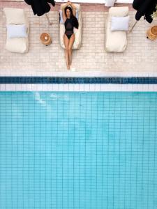 莫奈姆瓦夏Akra Morea Hotel & Residences的坐在游泳池旁床边的女人