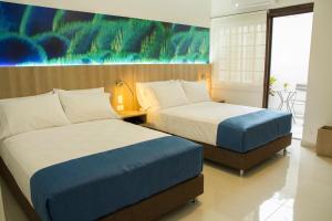 拉米萨Kau Hotel的酒店客房设有两张床,墙上挂有绘画作品