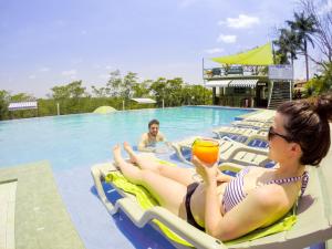 圣伊格纳西奥Rumors Resort Hotel的坐在游泳池里的木筏上喝一杯的女人