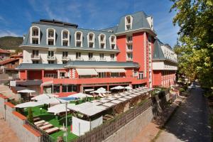 韦林格勒巴尔尼奥Spa水疗酒店的一座红色的大建筑,前面设有桌子和遮阳伞
