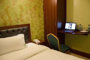 内罗毕白灰酒店的一间卧室配有一张床和一张桌子上的笔记本电脑
