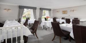 恩布尔顿The Dunstanburgh Castle Hotel的一间设有白色桌椅的用餐室