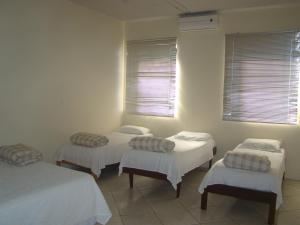 伊瓜苏普萨达跨提宾馆的配有白色墙壁和窗户的客房内的三张床