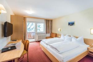 施坦察赫Hotel Garni Waldhof - Wohlfühlen am Lech的酒店客房设有一张大床和一张书桌。