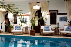 马拉喀什达尔阿尔法拉摩洛哥传统庭院住宅酒店的池畔客厅配有椅子和桌子