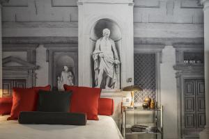 佛罗伦萨波迪赛丽酒店的一间设有一张床铺的客房,墙上挂着雕像