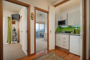 泰鲁阿帕库棕榈公寓的厨房配有白色橱柜,门通往阳台
