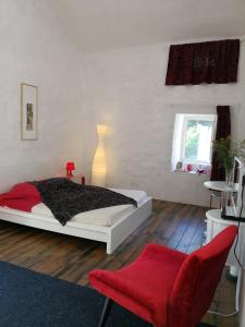Saint-Jean-et-Saint-Paul德高塔姆红磨坊住宿加早餐旅馆的一间卧室配有一张床和一张红色椅子
