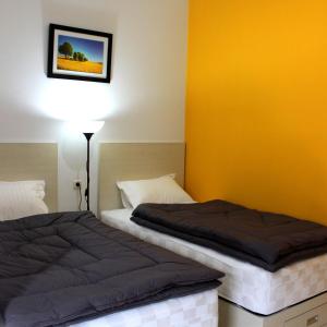 雅加达Rumah99的一间卧室设有两张床和黄色的墙壁