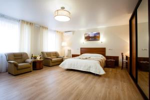 乌拉尔斯克APART-HOTEL VEGUS的一间卧室配有一张床、一张沙发和椅子
