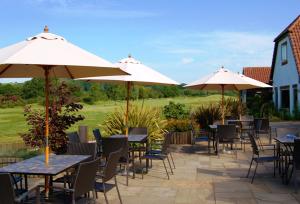 奥尔顿Blacknest Golf and Country Club的一个带桌椅和遮阳伞的庭院。
