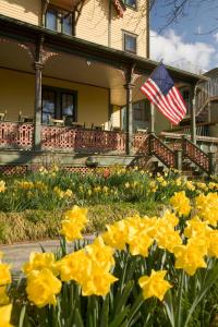 五月岬郡The Queen Victoria的一座有美国国旗和黄色花卉的房子