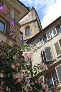 纳沙泰尔Le Café-Hôtel de L'Aubier的一座带钟楼和粉红色玫瑰的建筑