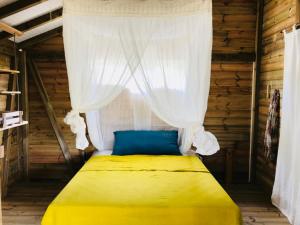 BeauséjourBungalow de charme vue mer的一间卧室配有一张黄色的床和窗帘