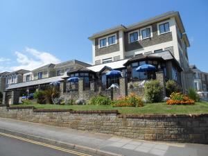 桑当The Wight Bay Hotel - Isle of Wight的前面有蓝色伞的大建筑