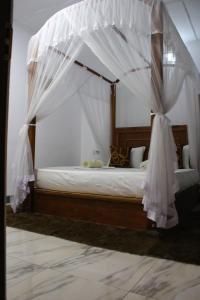 锡吉里亚Sigiriya Lahiru Homestay的卧室配有带白色窗帘的天蓬床