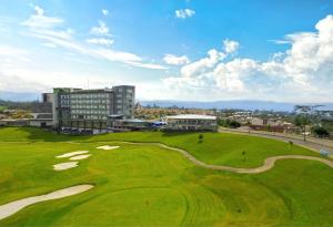 布卡拉曼加Punta Diamante Premium Hotel的一座绿色高尔夫球场,其建筑背景为: