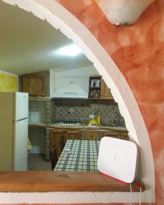 多尔加利Casa Aurora的厨房设有拱门,配有一张桌子和一台笔记本电脑