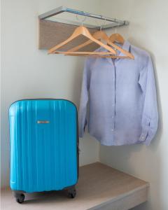 马尼拉Hop Inn Hotel Ermita Manila的衣柜里的一个蓝色手提箱和一件衬衫