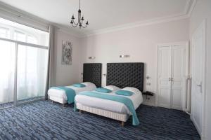 波城Hôtel Continental Pau Centre的一间卧室配有两张床和吊灯。