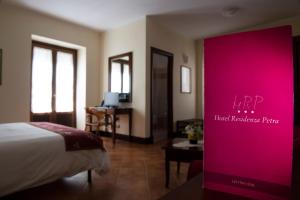 佩特拉利亚索普拉纳Hotel Residenza Petra的酒店客房,配有床铺和粉红色标志