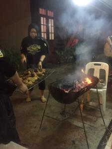 邦咯Nipahmas Chalet的一群人在烧烤架上烹饪食物