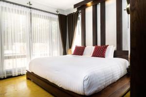 彭世洛Shinnabhura Historic Boutique Hotel的卧室配有带红色枕头的大型白色床