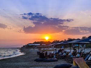 法纳里恩Villa Elaia Mare的一群人坐在海滩上,日落时分