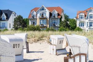 赛巴特班森Strandhotel Möwe的房屋前的海滩上摆放着一组椅子